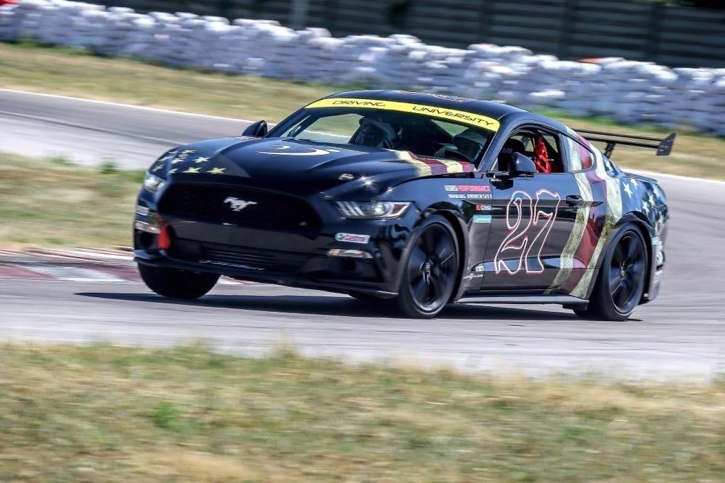 Mustang nera numero 27 in drift in pista durante un evento Driving University