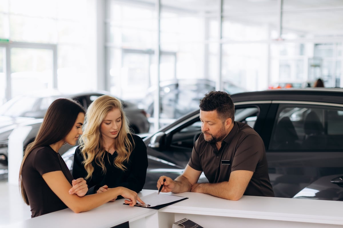 Sales advisor explaining an electric car to a customer inside a modern showroom
