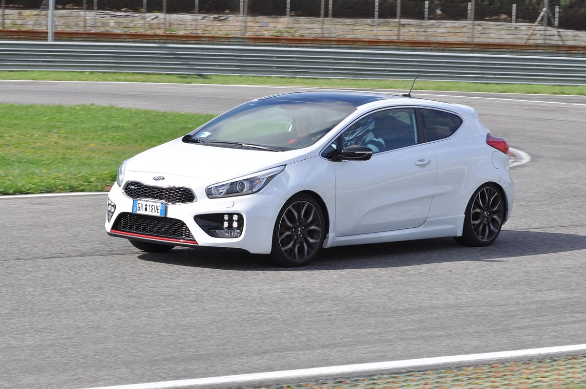 White Kia Ceed sportive hatchback on a race track with green grass and fencing in background