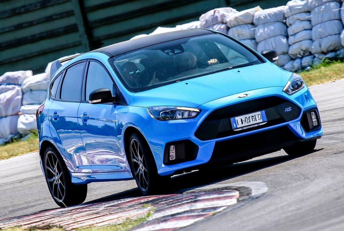 Bright blue Ford Focus RS hatchback parked on a track with white sandbags in the background