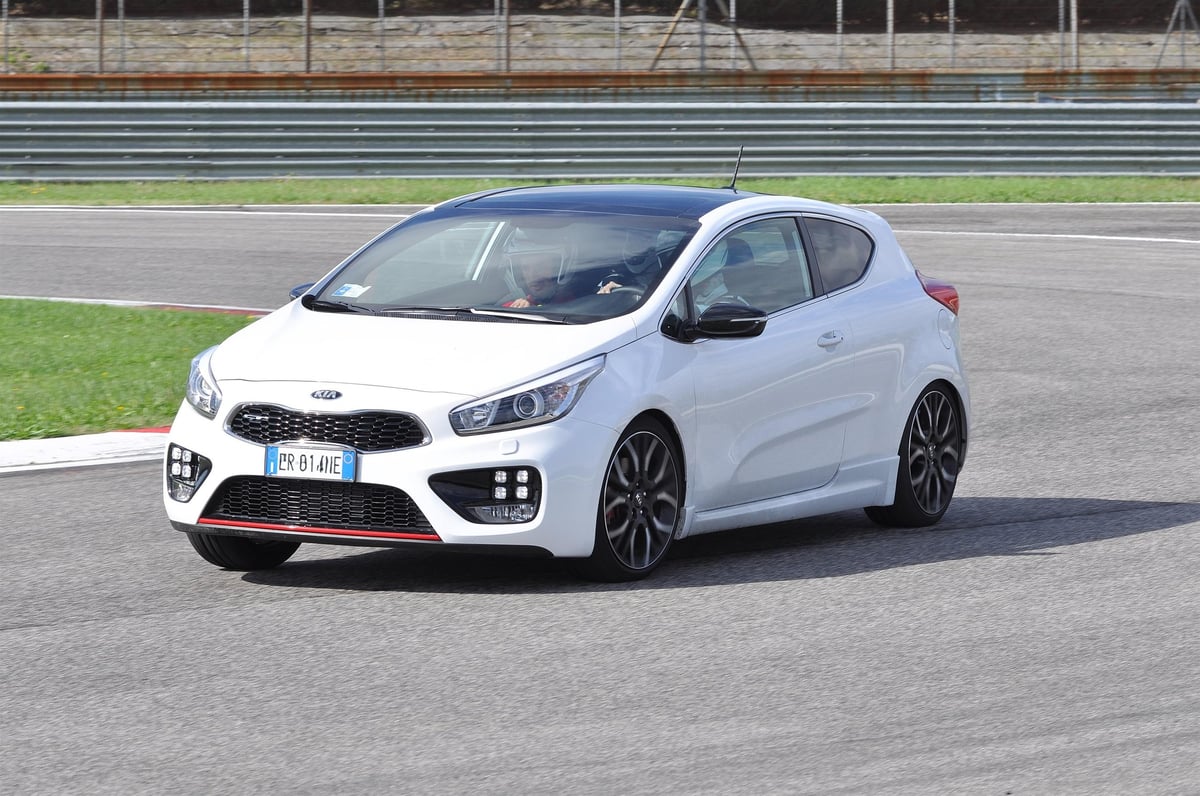 White Kia Pro Ceed sports car parked on a racing track with grandstands in the background