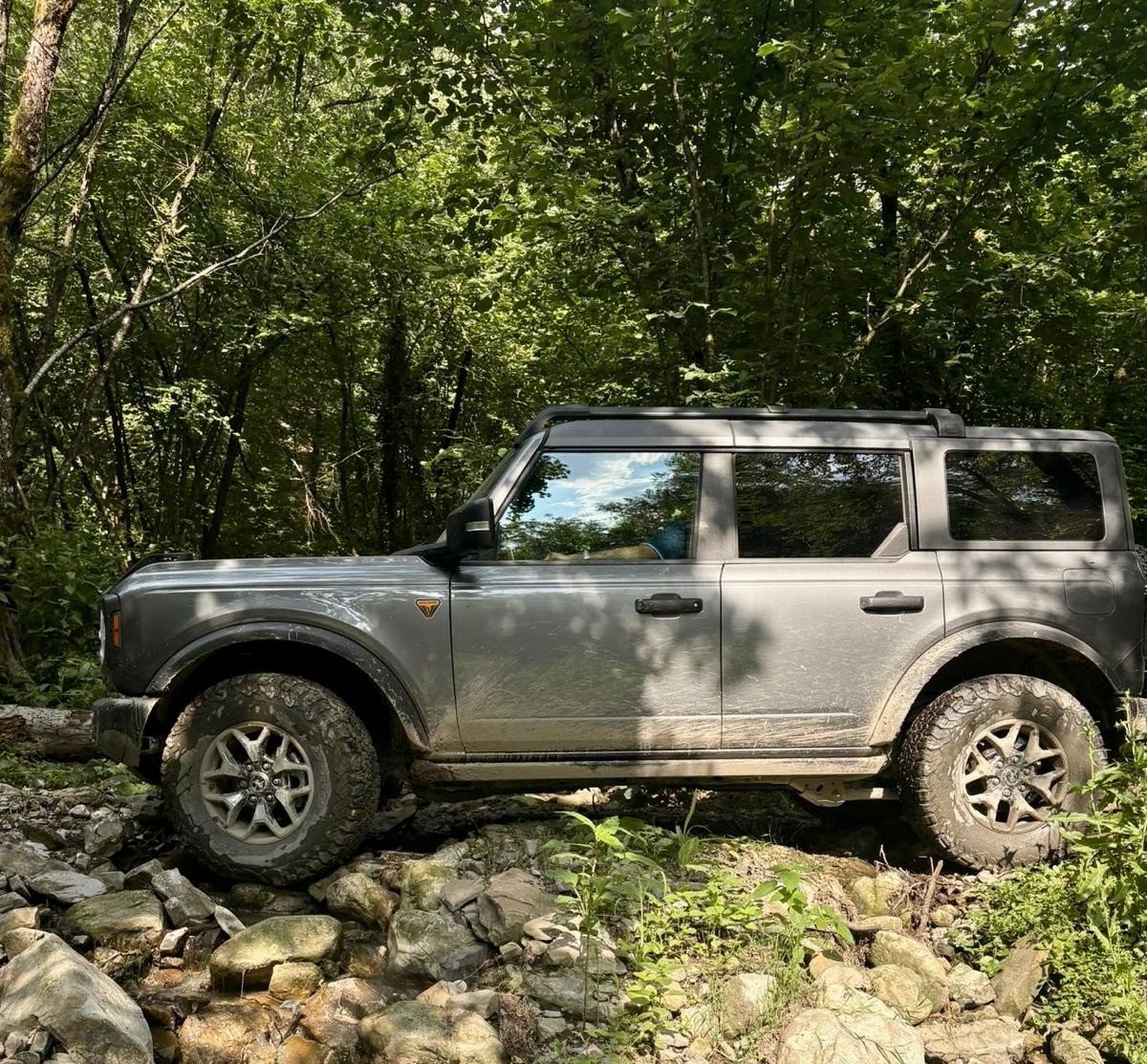 Land Rover Defender grigio su terreno roccioso nel bosco